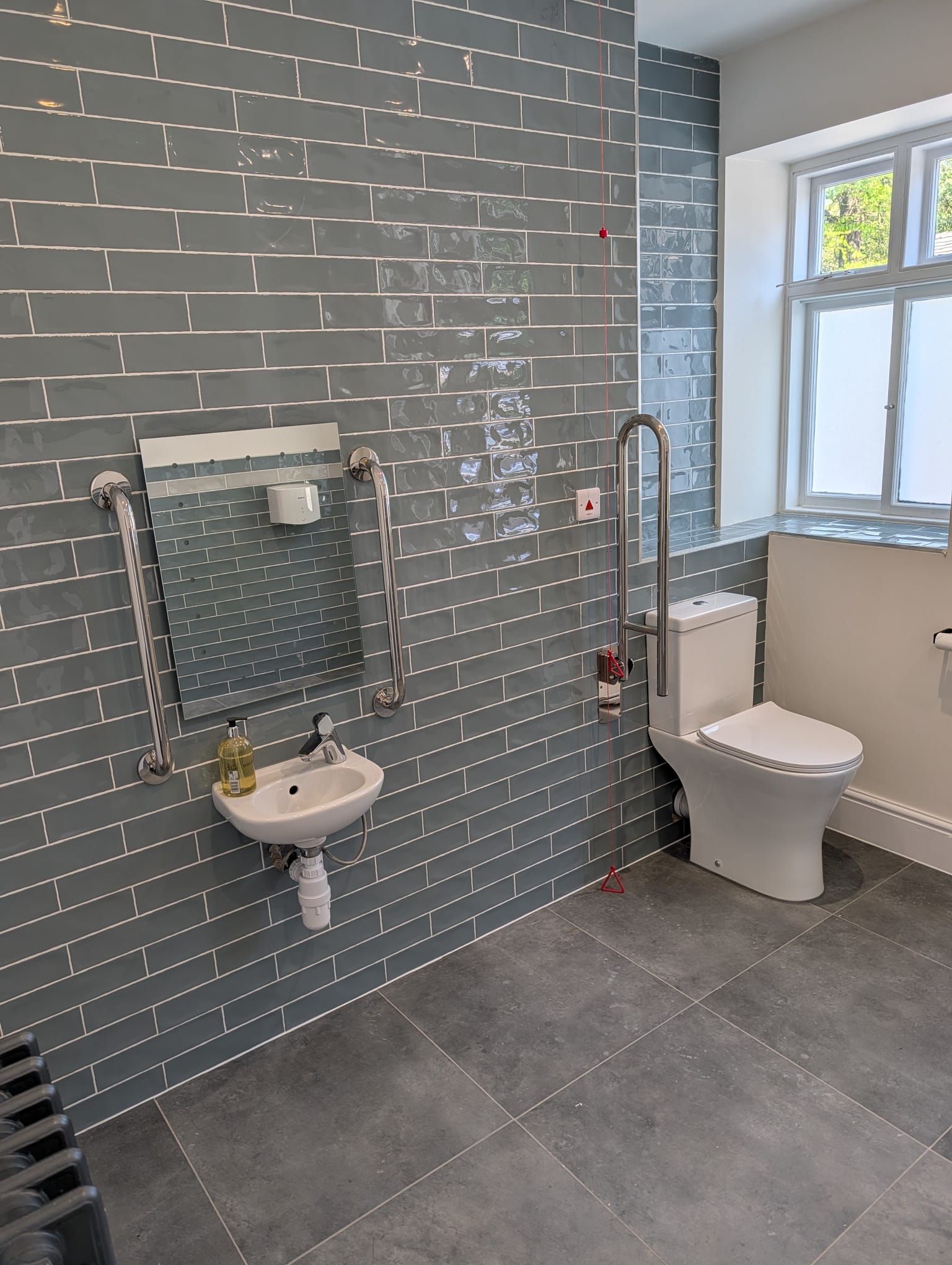 Grey subway tile accessible bathroom with grab rails